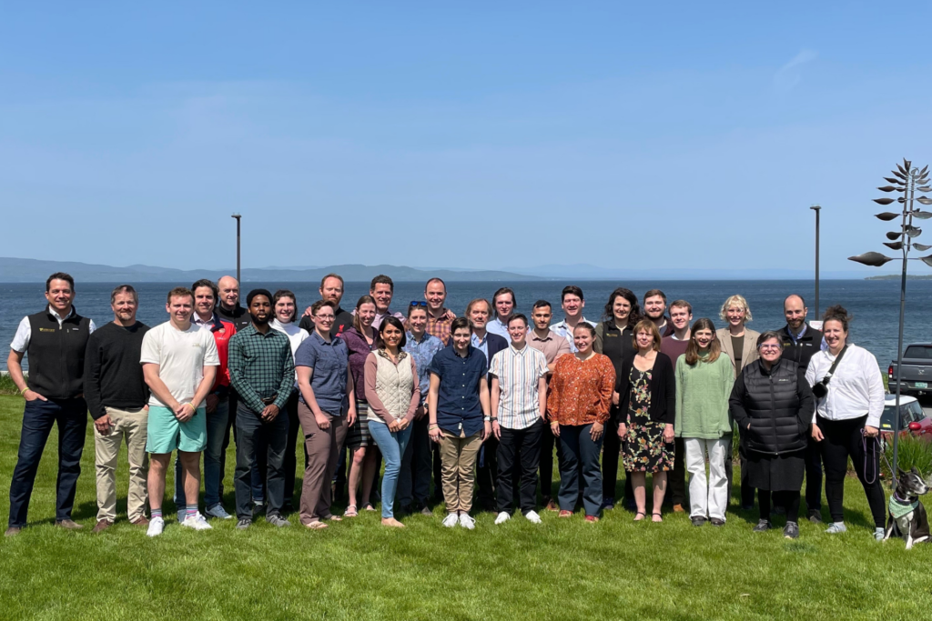 A recent photo of the Encore team, now more than 30 people, standing in front of Lake Champlain.