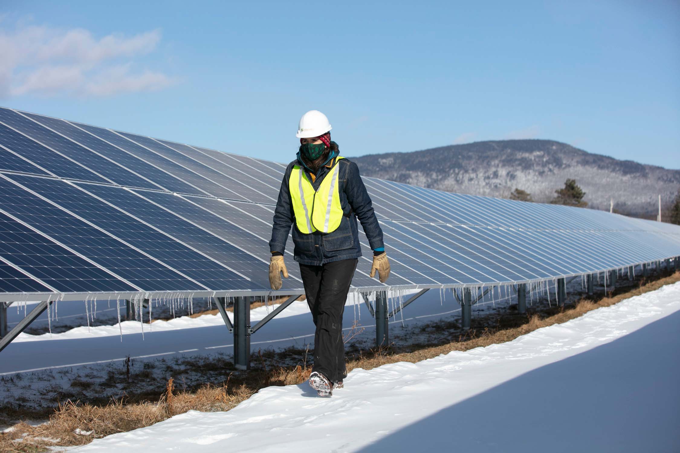 encore worker with facemask walking by solar array